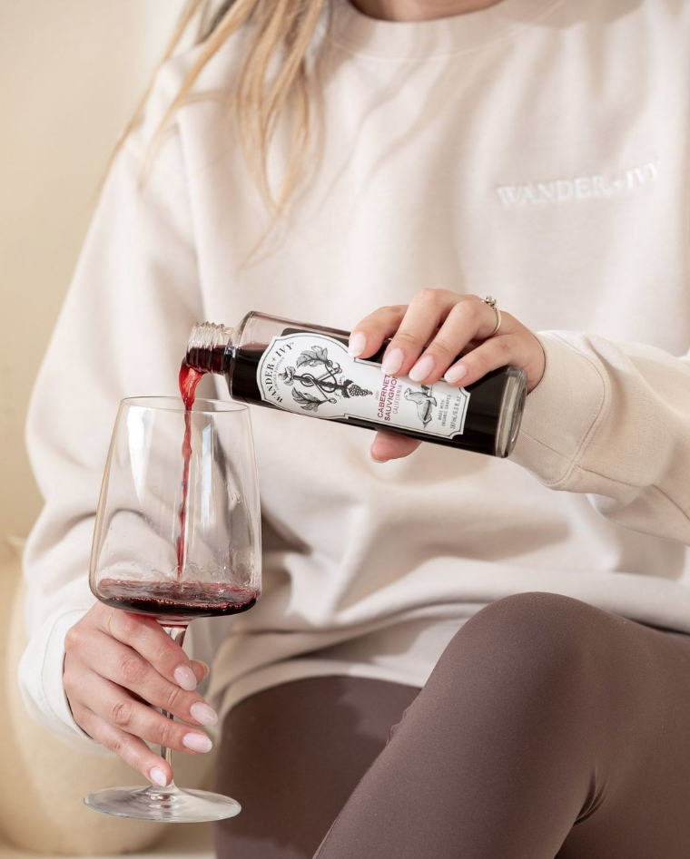 Woman pouring a Wander + Ivy red wine into a glass